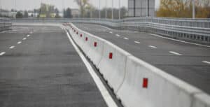 White precast concrete Jersey barriers with red reflectors lining a divided highway