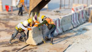 Workers install precast concrete barriers, showcasing their role in strengthening disaster-resilient infrastructure.