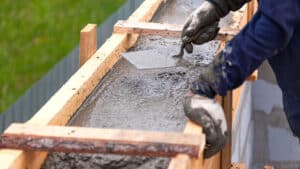 Precast concrete being poured and shaped in a wooden mold, showcasing sustainable construction practices and off-site production methods.